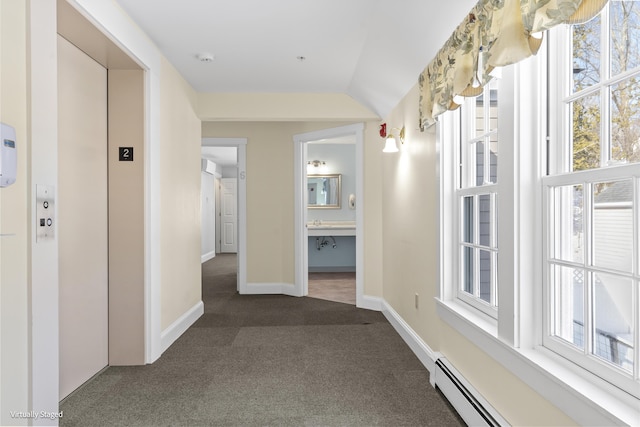 hall with lofted ceiling, a baseboard radiator, baseboards, dark colored carpet, and elevator