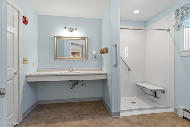 bathroom featuring a stall shower, baseboards, a baseboard heating unit, and a sink