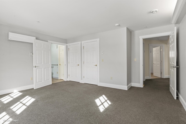 unfurnished bedroom with dark colored carpet, an AC wall unit, and baseboards