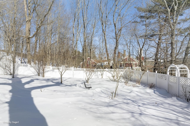 snowy yard featuring a fenced backyard