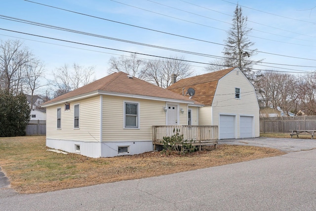 view of front facade featuring a front yard, a garage, and a wooden deck