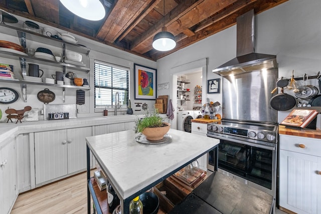 kitchen with wooden ceiling, hanging light fixtures, wall chimney range hood, white cabinets, and washer and dryer