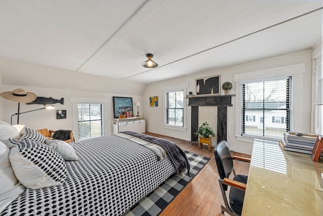 bedroom with multiple windows, wood-type flooring, and vaulted ceiling