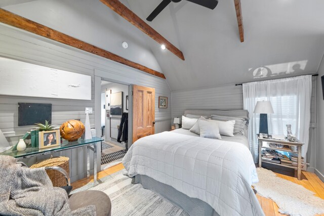 bedroom with wood walls, ceiling fan, lofted ceiling with beams, and light wood-type flooring