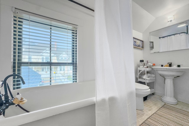 bathroom with tile patterned floors, a healthy amount of sunlight, toilet, and lofted ceiling