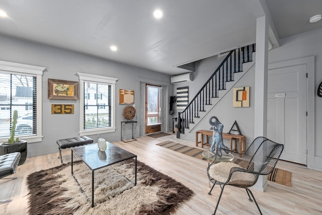 living room with a wall mounted AC and light hardwood / wood-style flooring