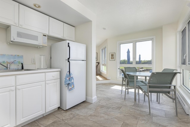 kitchen featuring white appliances, white cabinetry, and sink