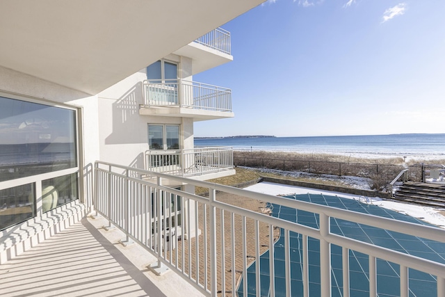 balcony featuring a view of the beach and a water view