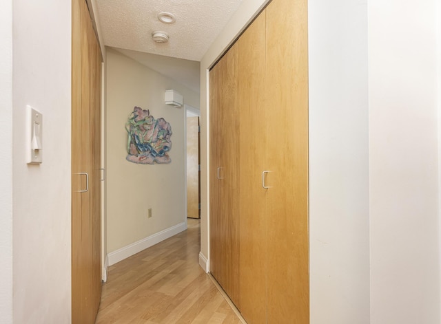 hall featuring a textured ceiling and light wood-type flooring