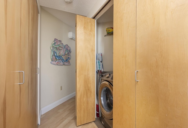 laundry room featuring a textured ceiling, light hardwood / wood-style floors, and washer / dryer