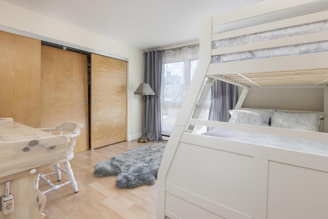 bedroom featuring baseboard heating, light wood-type flooring, and a closet