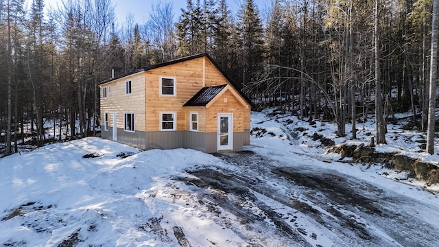 snow covered property featuring a wooded view