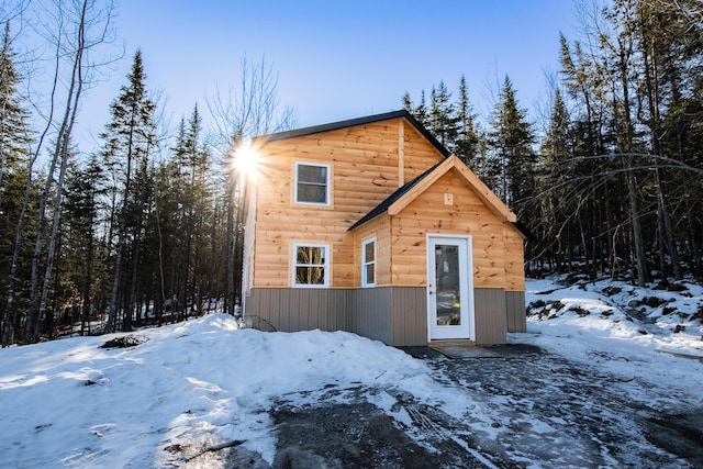 snow covered property with faux log siding