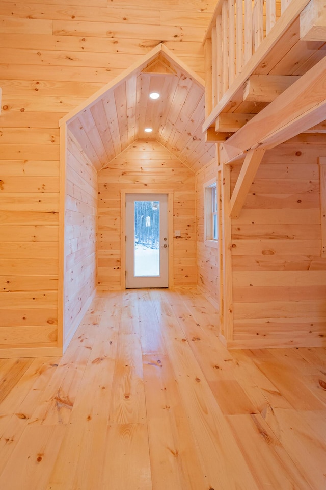 bonus room featuring lofted ceiling, wood walls, and light wood-style flooring