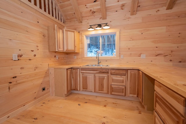 kitchen featuring light wood finished floors, wooden walls, wooden ceiling, light countertops, and a sink