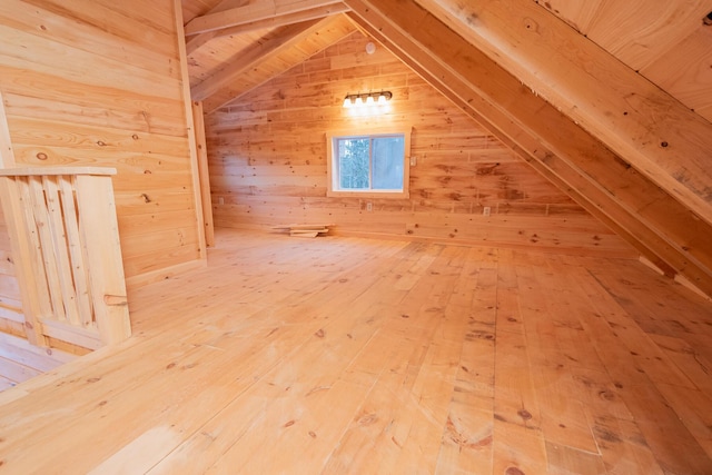 additional living space featuring lofted ceiling, hardwood / wood-style floors, and wooden walls