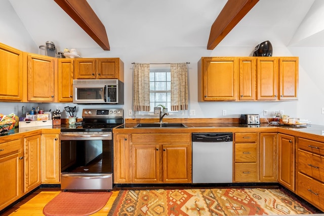 kitchen with vaulted ceiling with beams, sink, light wood-type flooring, and appliances with stainless steel finishes