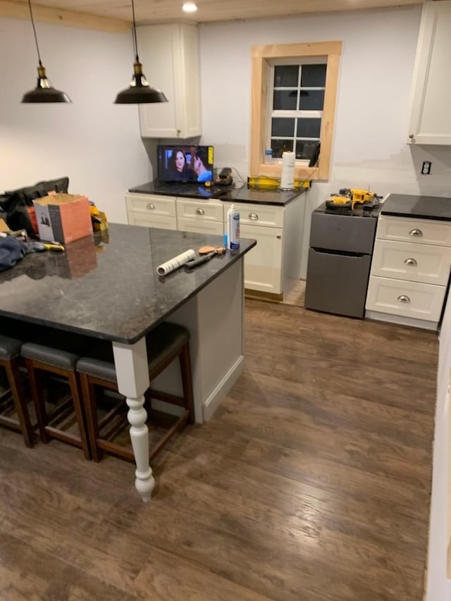 kitchen featuring decorative light fixtures, a kitchen breakfast bar, white cabinetry, and stainless steel refrigerator