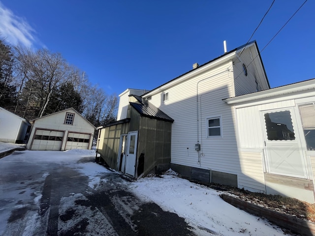 view of snowy exterior with a garage and an outdoor structure