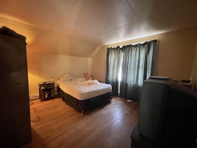 bedroom featuring a baseboard radiator, wood-type flooring, and vaulted ceiling