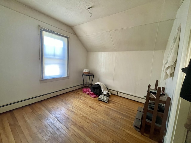 bonus room with hardwood / wood-style floors, a textured ceiling, baseboard heating, and vaulted ceiling