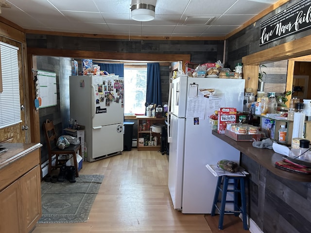 kitchen with wooden walls, white fridge, and light hardwood / wood-style floors