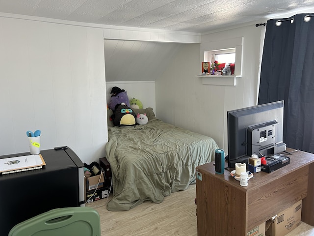 bedroom with wood walls and light hardwood / wood-style floors