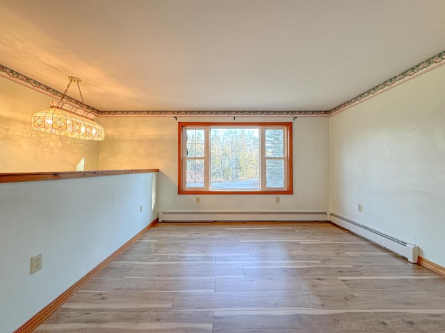 unfurnished room featuring a chandelier, light wood-type flooring, and a baseboard heating unit