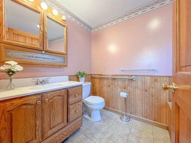 bathroom featuring tile patterned flooring, vanity, toilet, and wood walls