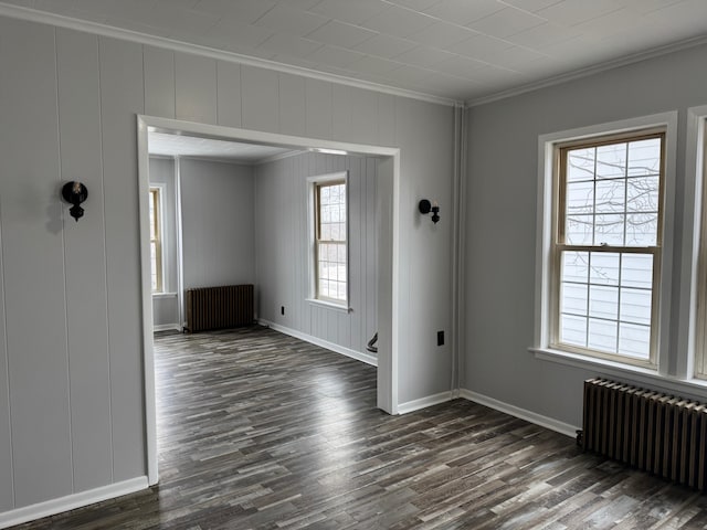 spare room with dark wood-type flooring, radiator, and crown molding