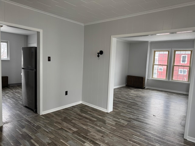 spare room with crown molding, radiator, and dark wood-type flooring