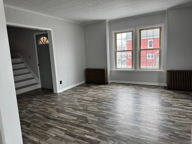 spare room with dark hardwood / wood-style flooring, radiator, and ornamental molding