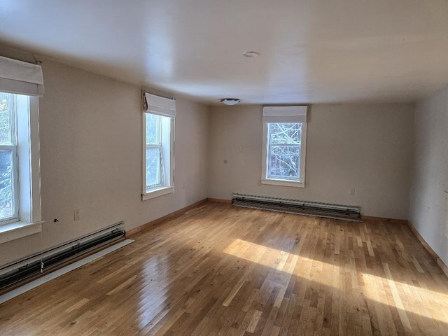 spare room featuring baseboard heating and wood-type flooring