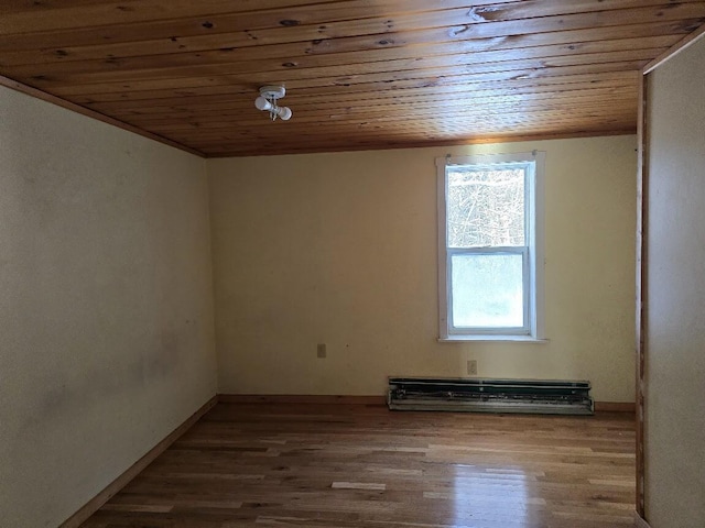 empty room with wood-type flooring, a baseboard heating unit, a wealth of natural light, and wooden ceiling