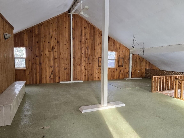 bonus room with lofted ceiling with beams, ceiling fan, carpet floors, and wooden walls