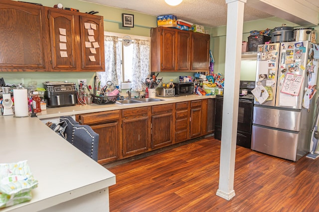 kitchen with decorative columns, a textured ceiling, dark wood-type flooring, sink, and black appliances