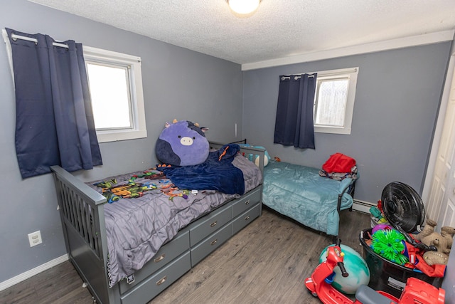 bedroom featuring wood-type flooring, a textured ceiling, and baseboard heating