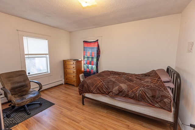 bedroom featuring light hardwood / wood-style flooring, a baseboard radiator, and a textured ceiling