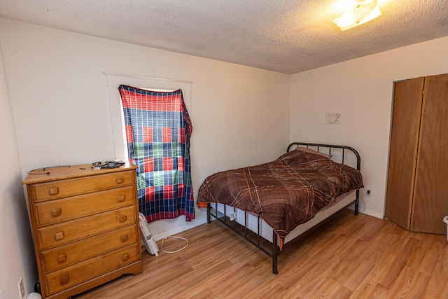 bedroom with light wood-type flooring and a textured ceiling