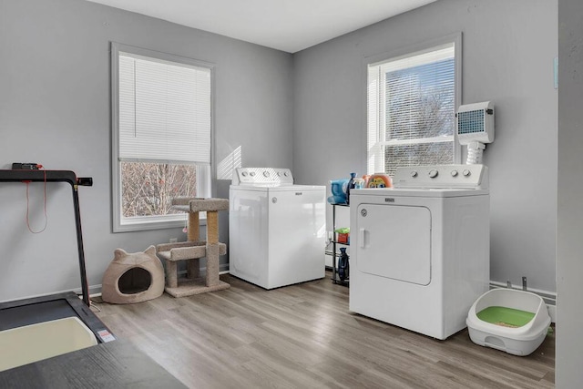 washroom with washing machine and clothes dryer and light wood-type flooring