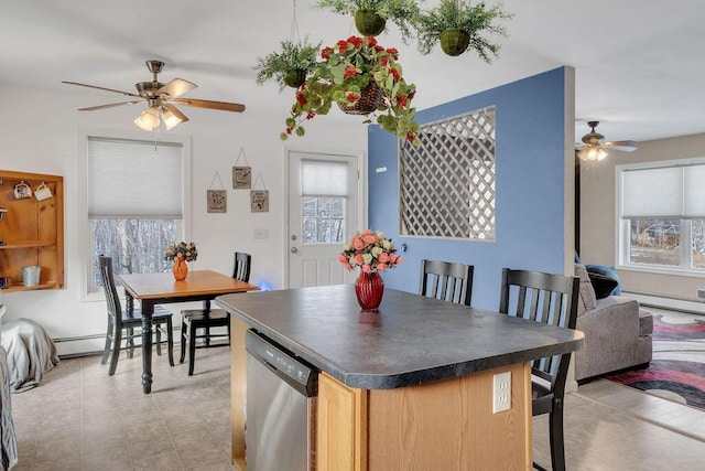 kitchen featuring stainless steel dishwasher, a baseboard radiator, ceiling fan, and a healthy amount of sunlight