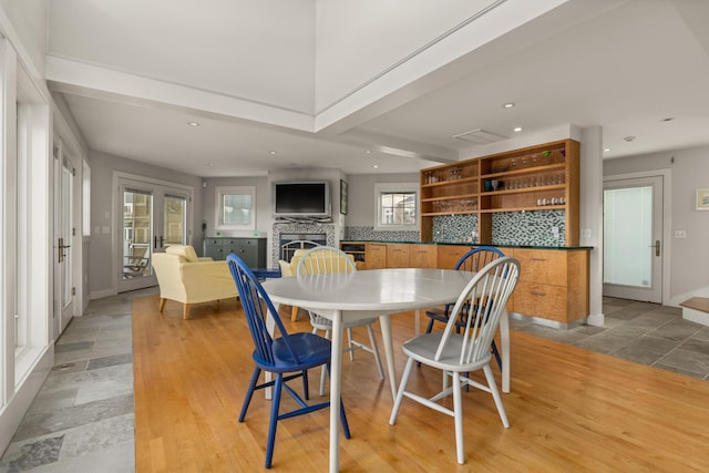 dining space featuring beamed ceiling, french doors, and light hardwood / wood-style floors