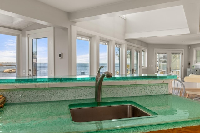 unfurnished sunroom featuring sink, a water view, and french doors