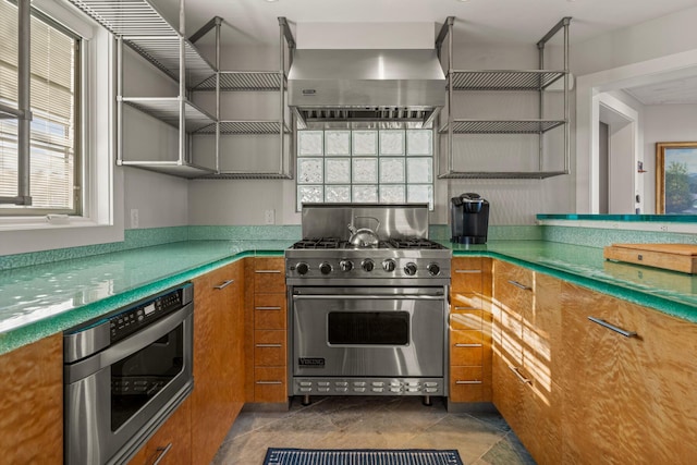 kitchen featuring plenty of natural light, designer range, wall chimney range hood, and dark tile patterned floors