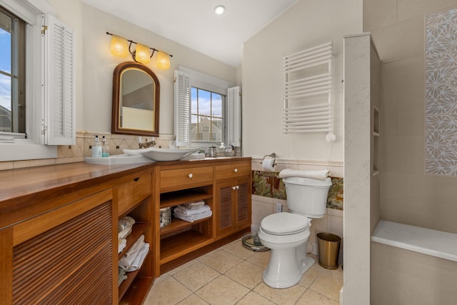 bathroom featuring radiator, tile patterned flooring, toilet, vanity, and tile walls