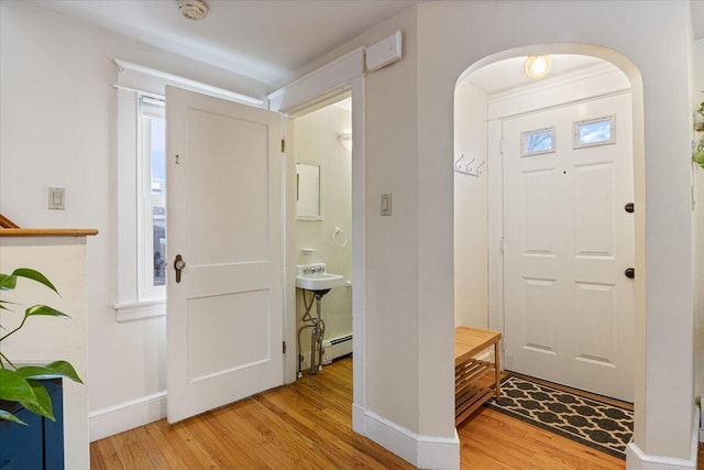 foyer entrance with light hardwood / wood-style floors, baseboard heating, and sink