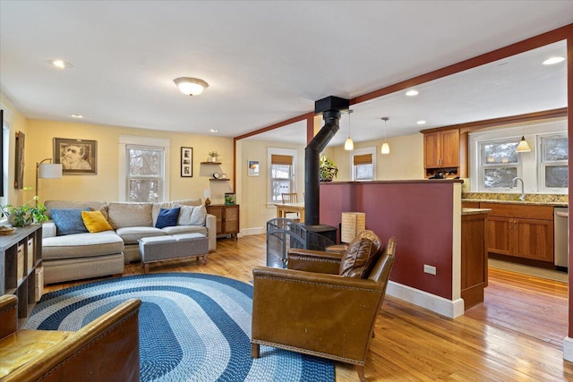 living room featuring light hardwood / wood-style floors, sink, and a wood stove