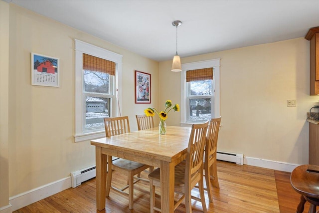 dining room with a baseboard heating unit, light wood-type flooring, and a wealth of natural light