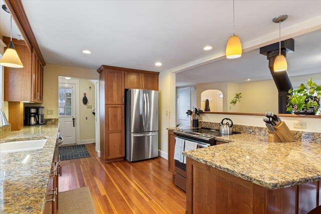 kitchen with stainless steel appliances, sink, pendant lighting, and light stone counters