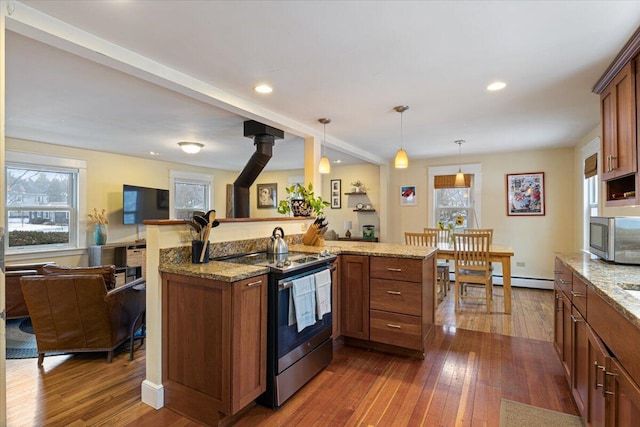 kitchen with kitchen peninsula, dark wood-type flooring, pendant lighting, a wood stove, and appliances with stainless steel finishes